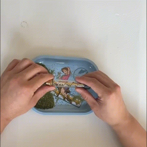 How to use a Twisty Glass Blunt by loading herb into the tube and twisting the handle over a blue rolling tray